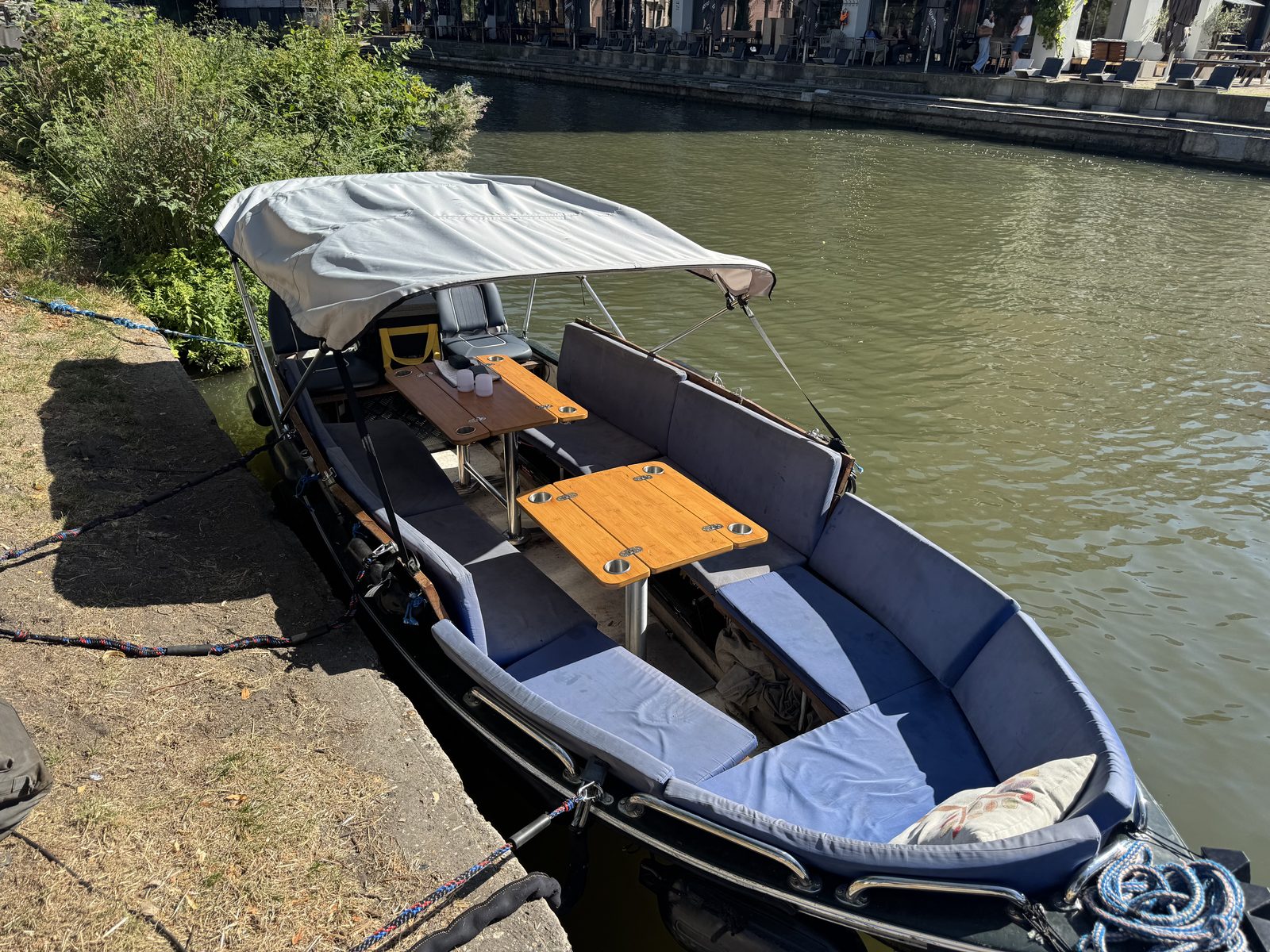 The boat with its bimini top up, seen from the quay